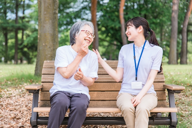 公園で話す高齢者と笑顔の介護スタッフ女