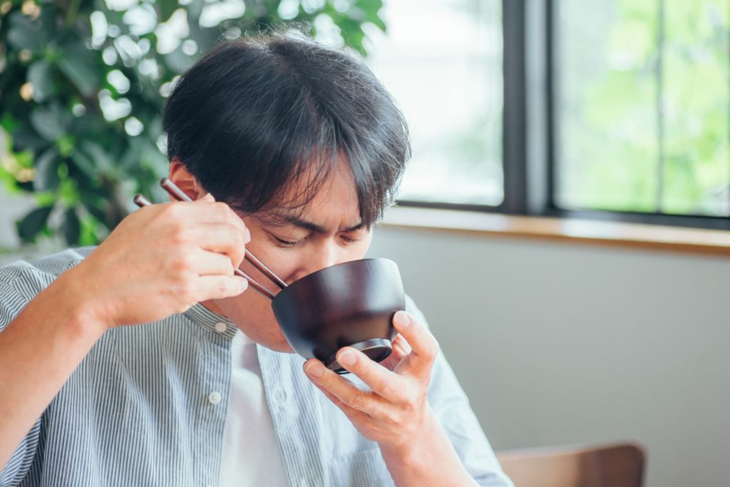 暖かい汁を飲む男性（味噌汁、スープ）