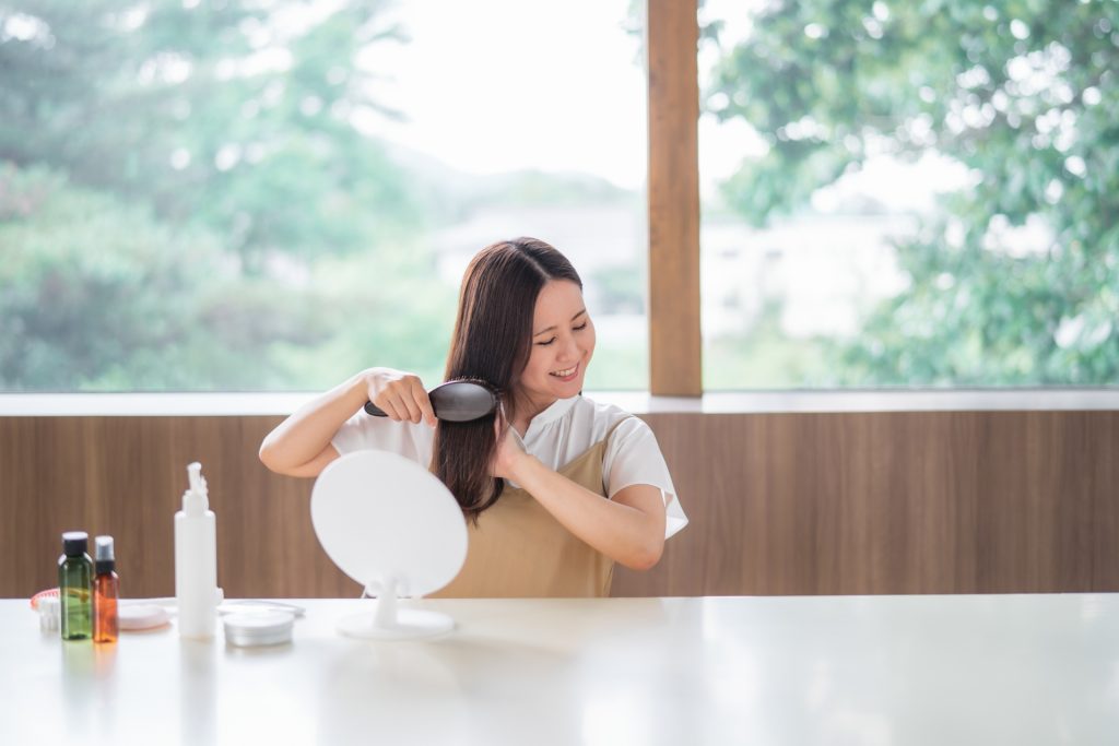 ヘアブラシで髪を梳かす女性