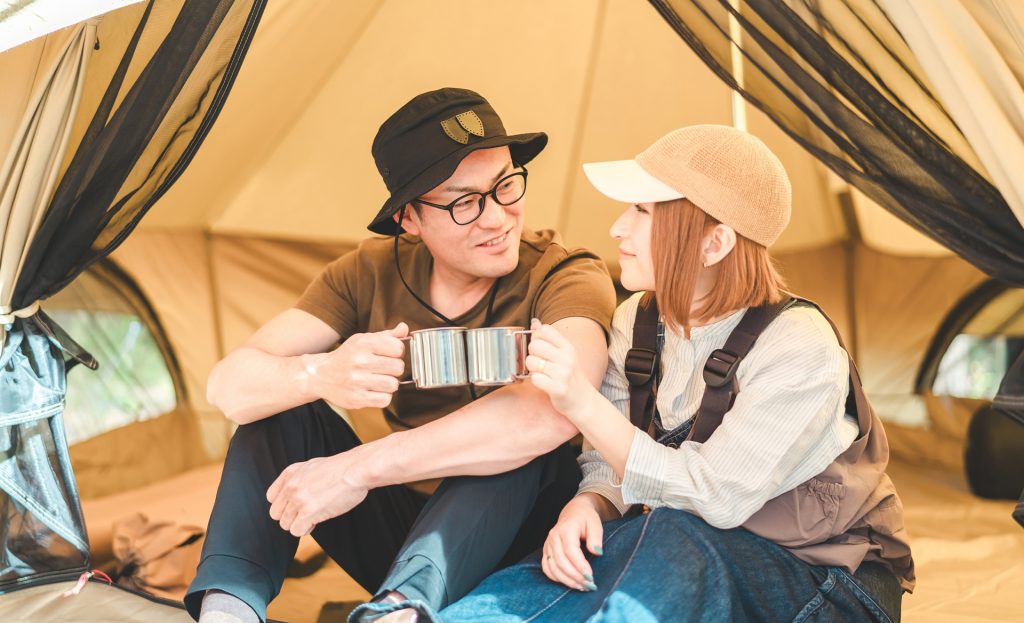 テントの中でマグカップで乾杯する男女