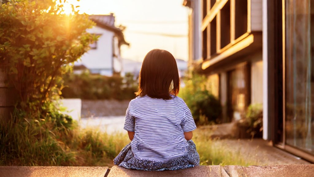 家の前で寂しそうに待つ幼い女の子
