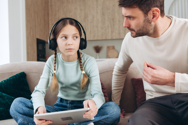 ソファに座って娘と会話をする父親の様子。丁寧に整えられた髭が落ち着きと品格を感じさせる家族のひととき