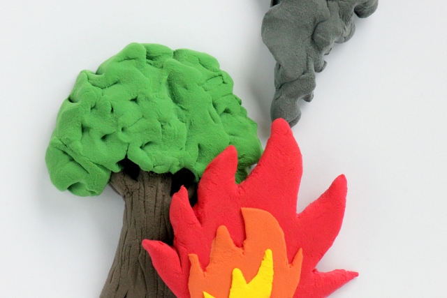 布アートで描かれた、木に燃え広がる火災と立ち上る煙のイメージ。芝刈り機への給油中にガソリンが排気に引火し、4歳の少年ミッチェルが火傷を負った事故を象徴的に表現した視覚演出。