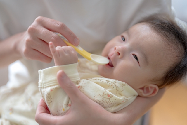 スプーンを口に運ぶ赤ちゃん